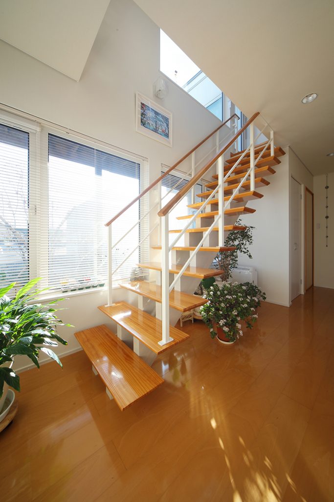 軽やかなデザインのスケルトン階段。窓の向こうには庭の緑を望む