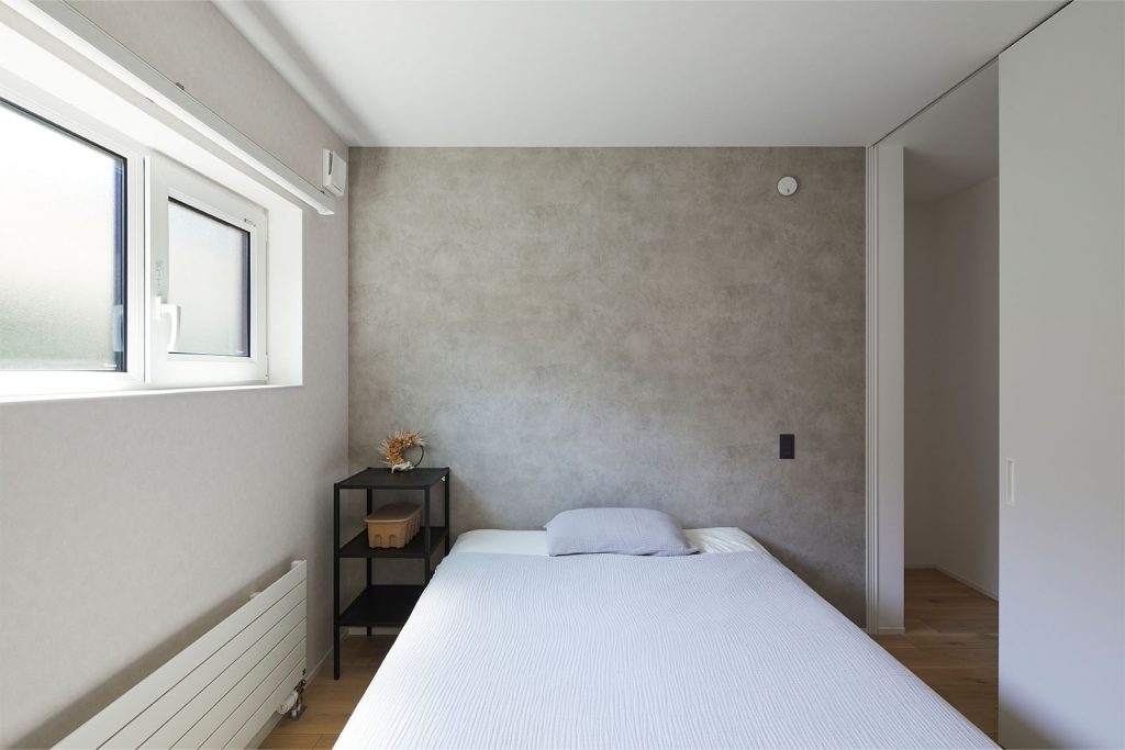 塗り壁風の壁紙をあしらった寝室。シンプルで飽きのこないデザインが魅力