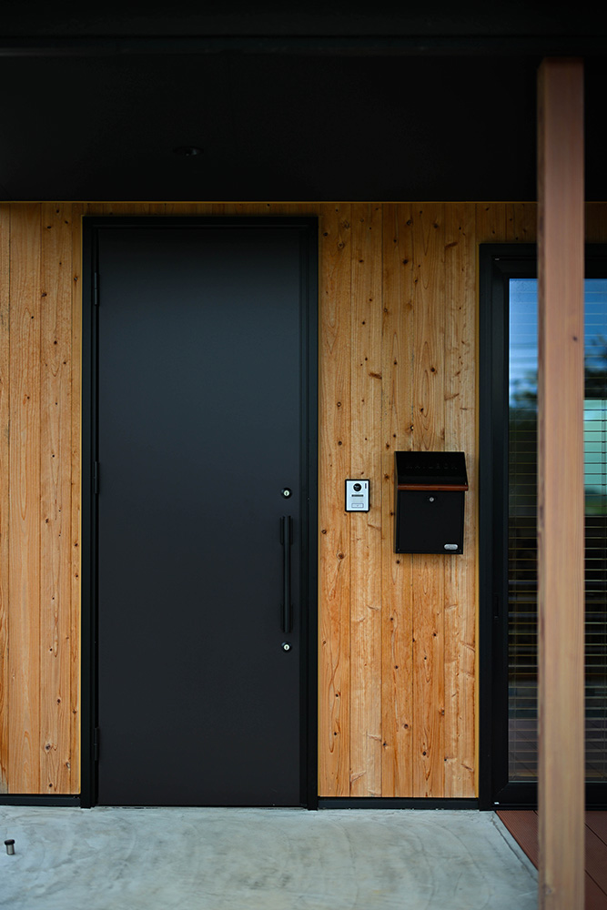 玄関やウッドデッキまわりの外壁面に張った屋久島地杉が、ファサードに温もりをプラス